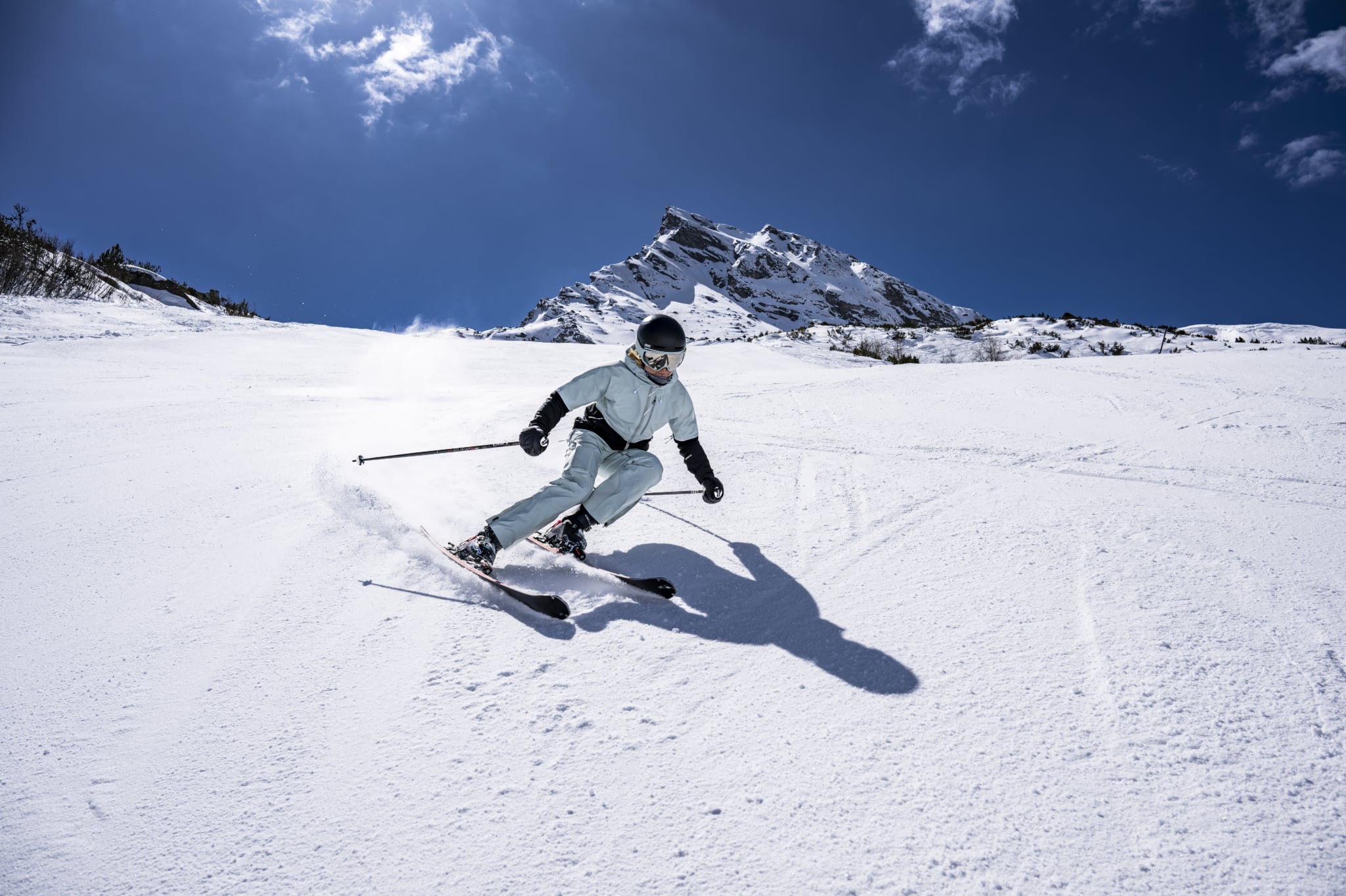 Skifahrer auf einer schneebedeckten Piste vor einer Berglandschaft.