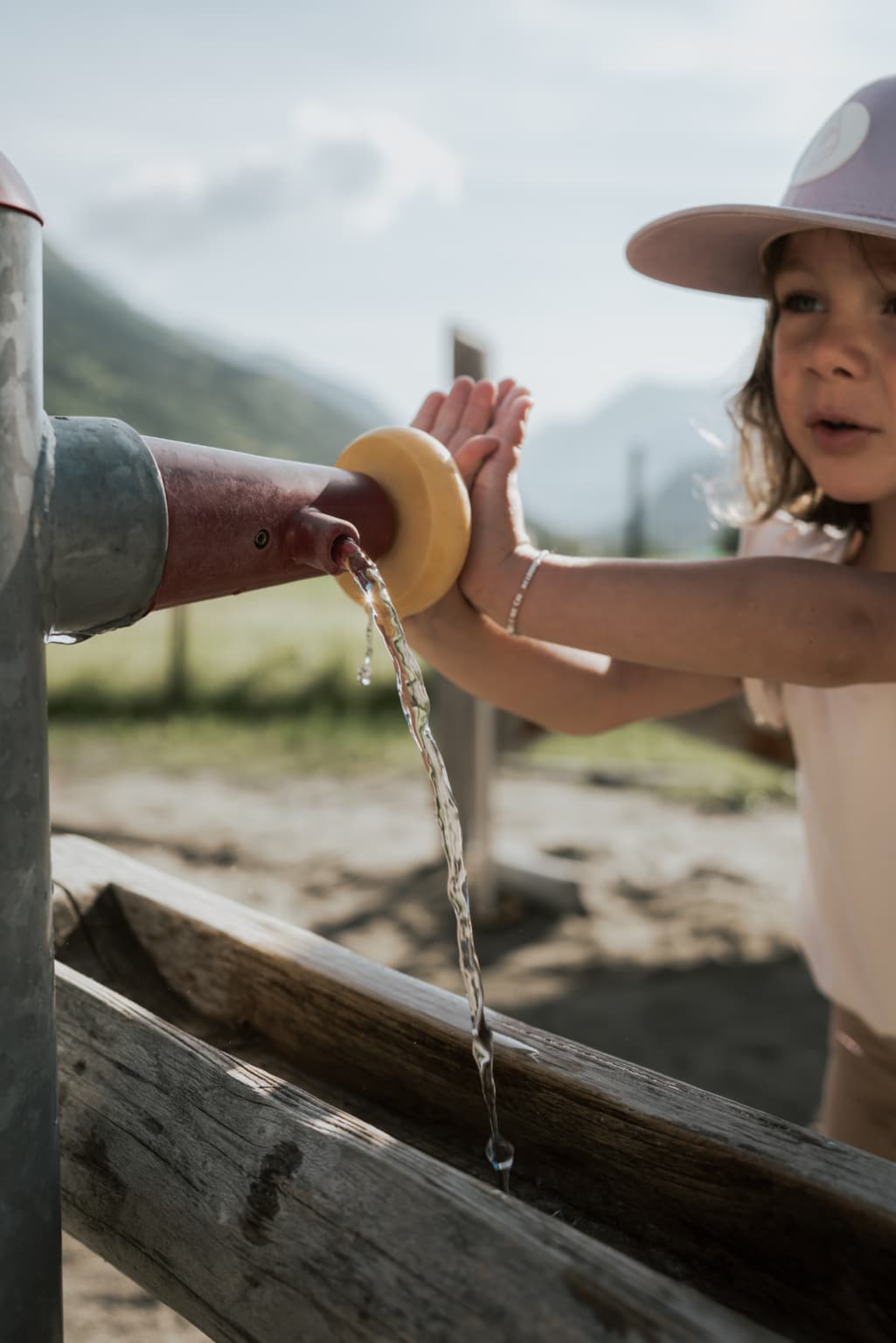 Ein Kind spielt an einem Wasserpumpensystem auf einem Spielplatz in der Natur.