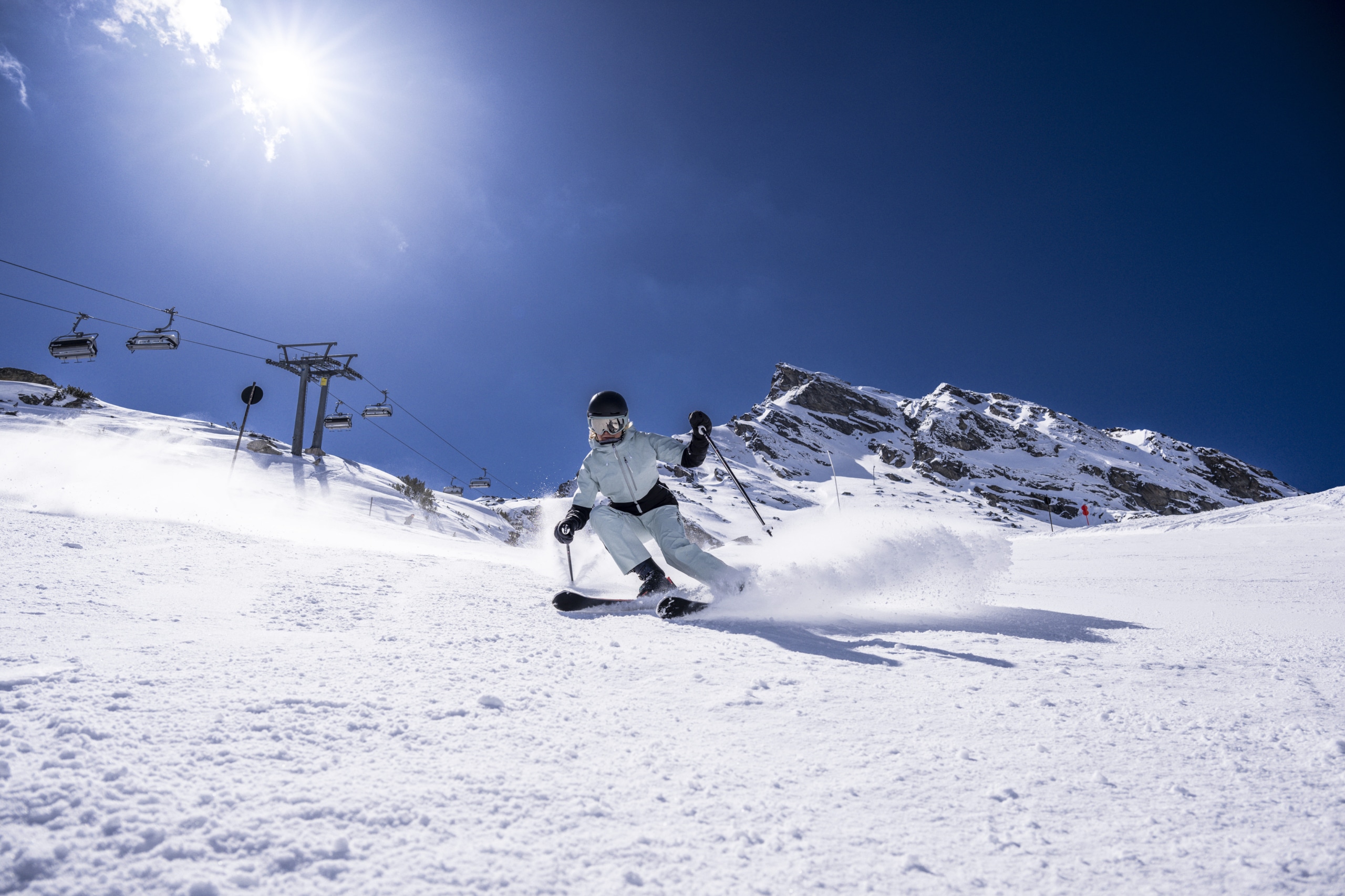 Skifahrerin zieht eine dynamische Kurve auf einer sonnigen Skipiste in Galtür in Tirol.