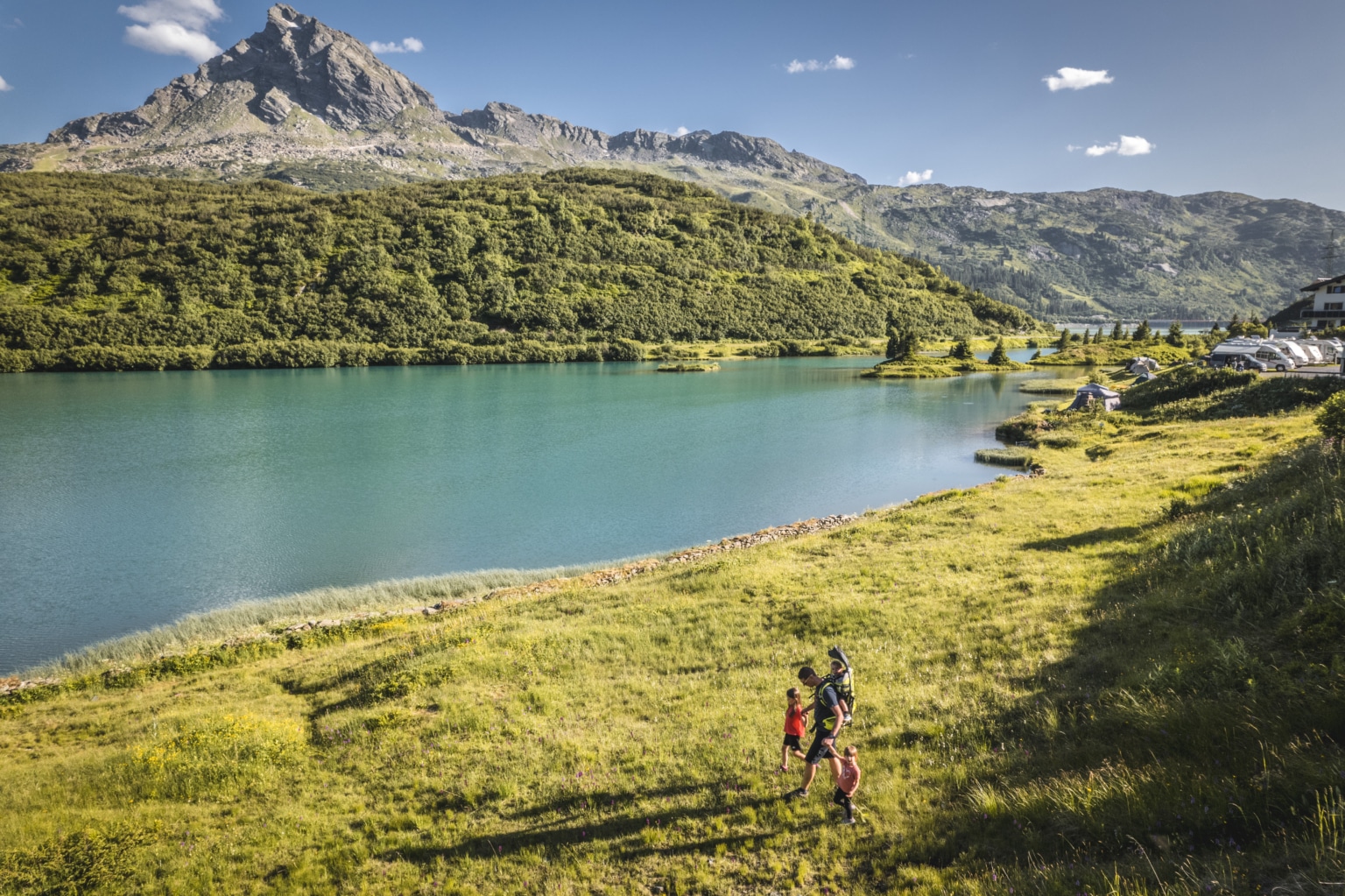 Familie mit Kindern beim Wandern am Zeinissee in Galtür, Tirol. Türkisblauer Bergsee, beeindruckende Alpenlandschaft und familienfreundliche Wanderwege im Paznaun.